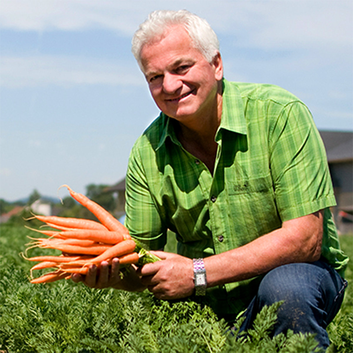 Maraîcher dans un champ avec des carottes à la main